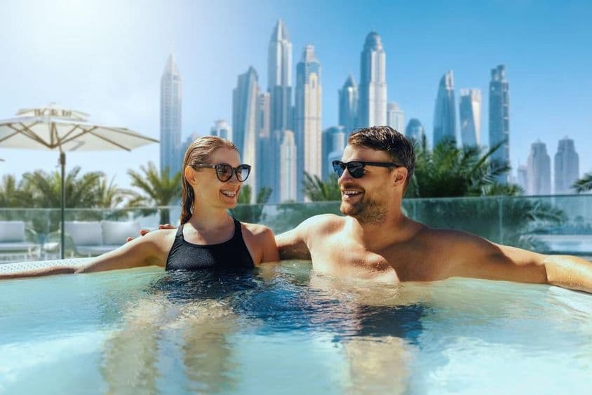 Pareja joven feliz se relaja en un jacuzzi al aire libre en un hotel de Dubái.