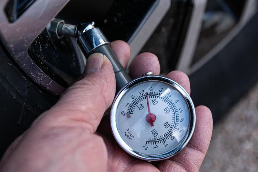 Revisar la presión de los neumáticos con un manómetro para el inflado adecuado en una llanta de automóvil.