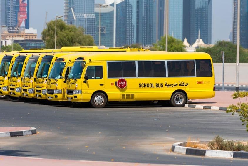 Autobuses escolares amarillos en Dubái alineados y estacionados afuera.
