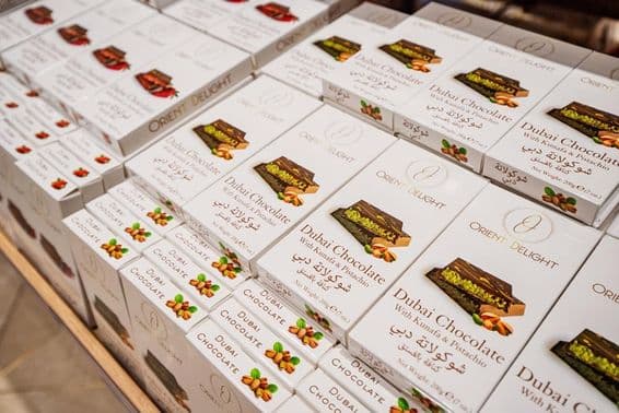 Barras de chocolate de Dubái rellenas de kunafa y pistacho apiladas en estante de tienda.