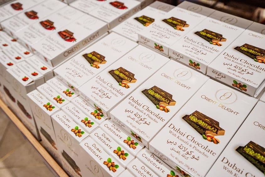 Barras de chocolate de Dubái rellenas de kunafa y pistacho apiladas en estante de tienda.