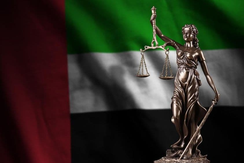 La bandera de los Emiratos Árabes Unidos con una estatua de la Dama de la Justicia.