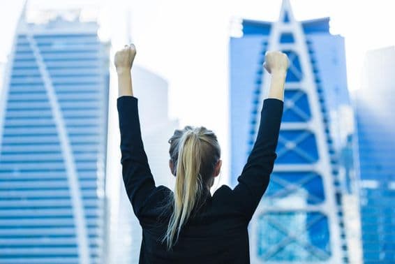 Mujer de negocios celebrando el éxito con vista al centro de Dubái.