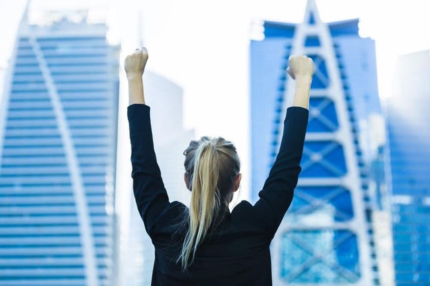 Mujer de negocios celebrando el éxito con vista al centro de Dubái.