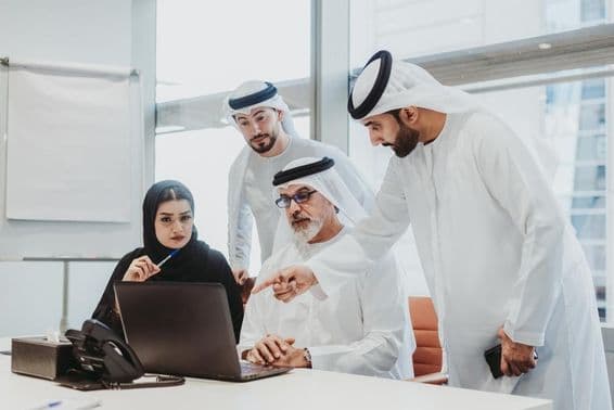 Empresarios vestidos con atuendo emiratí en reunión en una oficina en Dubái.