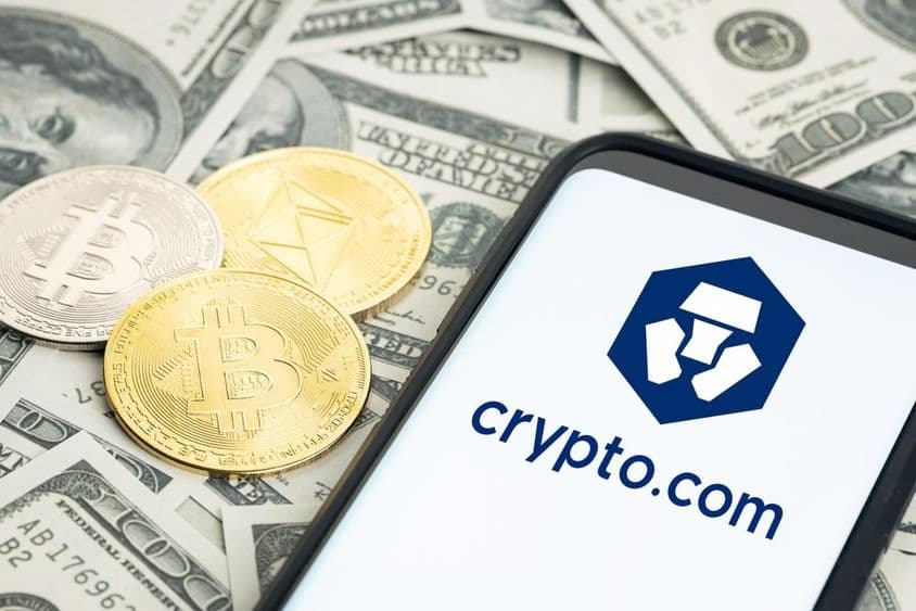 Logo de Crypto.com, fajos de dólares, monedas de Bitcoin y Ethereum visibles.