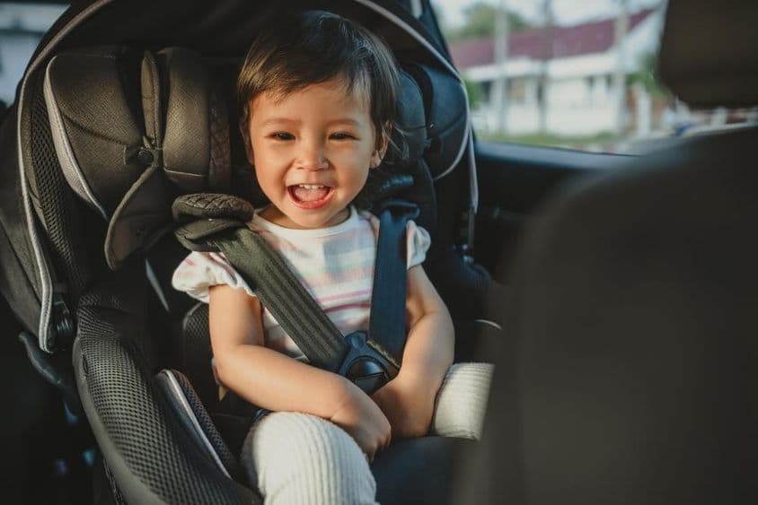 Niño feliz sentado en un asiento de coche.