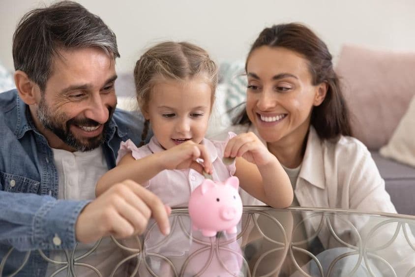 Padres felices enseñando a su hija a ahorrar dinero.