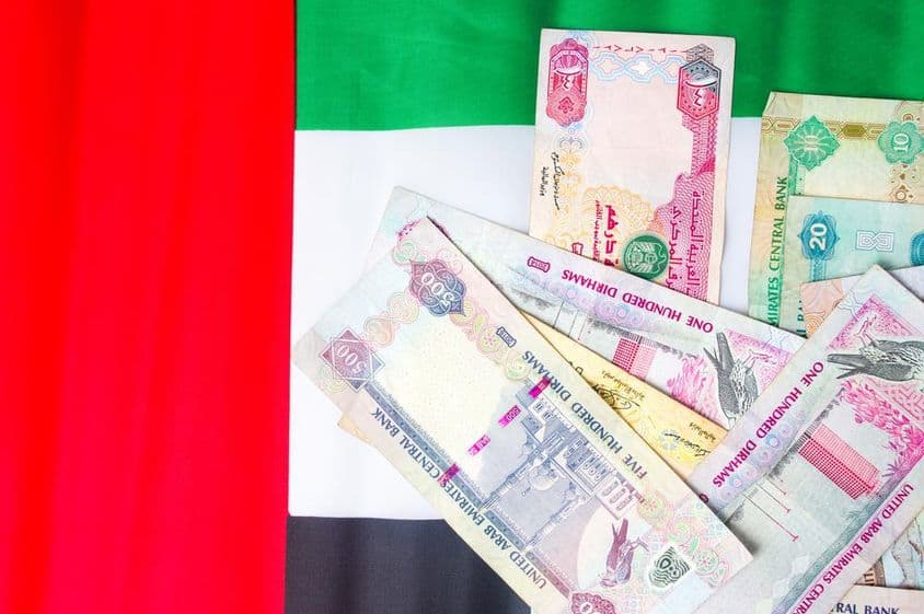 Billetes de dirham de EAU sobre la bandera nacional.
