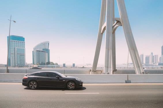 Coche Porsche Panamera negro circula por una calle de la ciudad de Dubái.