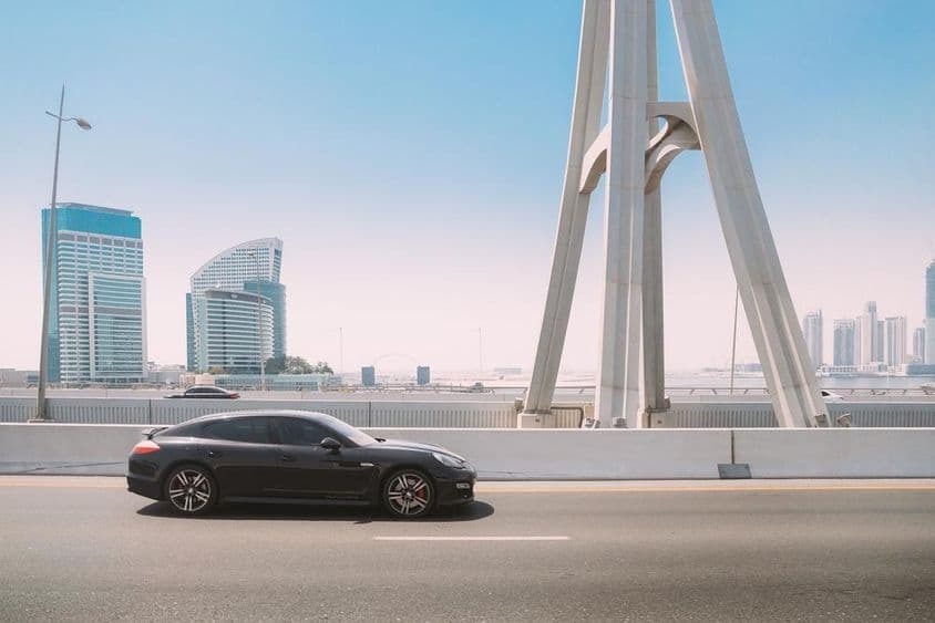 Coche Porsche Panamera negro circula por una calle de la ciudad de Dubái.
