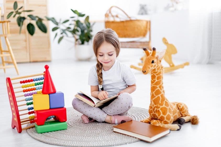 Una niña pequeña entre juguetes en una luminosa habitación infantil.