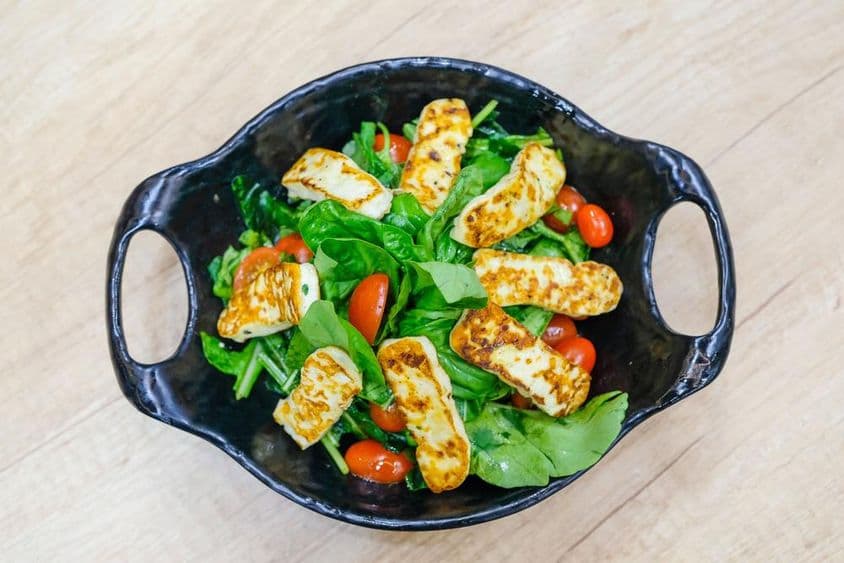 Ensalada de queso con hojas de rúcula y tomates cherry.