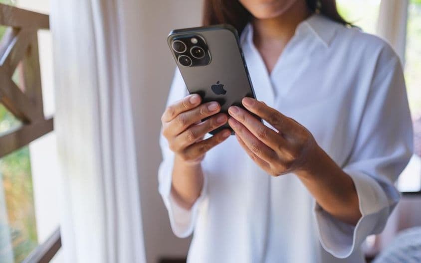 Una mujer usando un iPhone 15 Pro Max en casa.