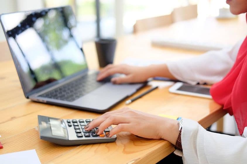 Trabajadora en Dubái calculando datos financieros con una calculadora.
