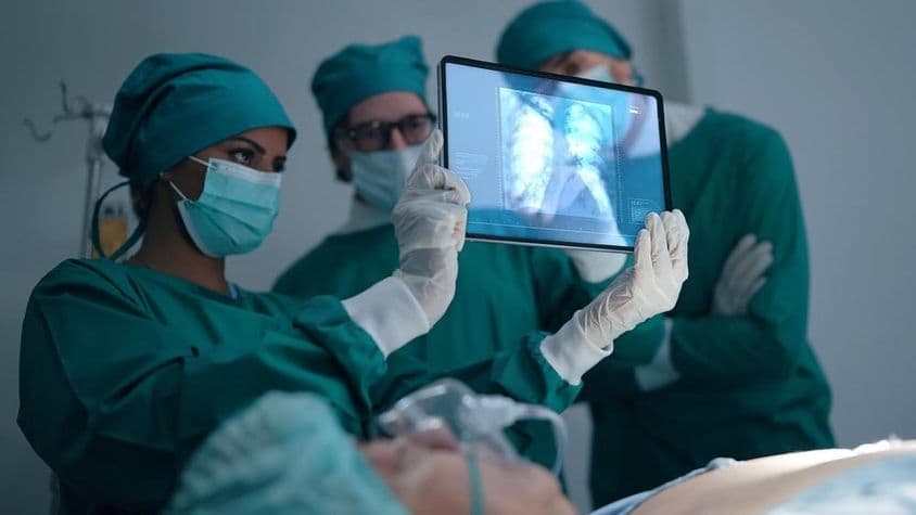 Equipo médico profesional discutiendo y revisando una radiografía de un paciente con neumonía.