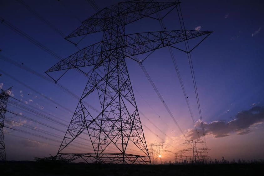Torres de alta tensión al atardecer con vista al paisaje urbano de Dubái.