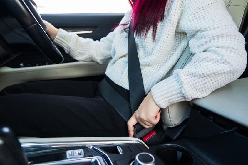 Conductora abrochándose el cinturón de seguridad.