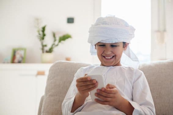 Niño árabe usando un smartphone en casa.