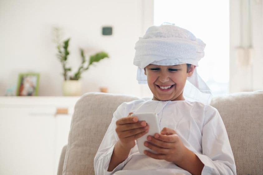 Niño árabe usando un smartphone en casa.