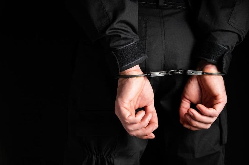 Manos de un criminal esposadas.