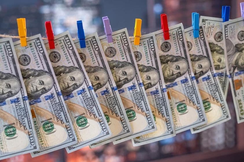 Un billete de 100 dólares colgando de un tendedero con pinzas de madera.