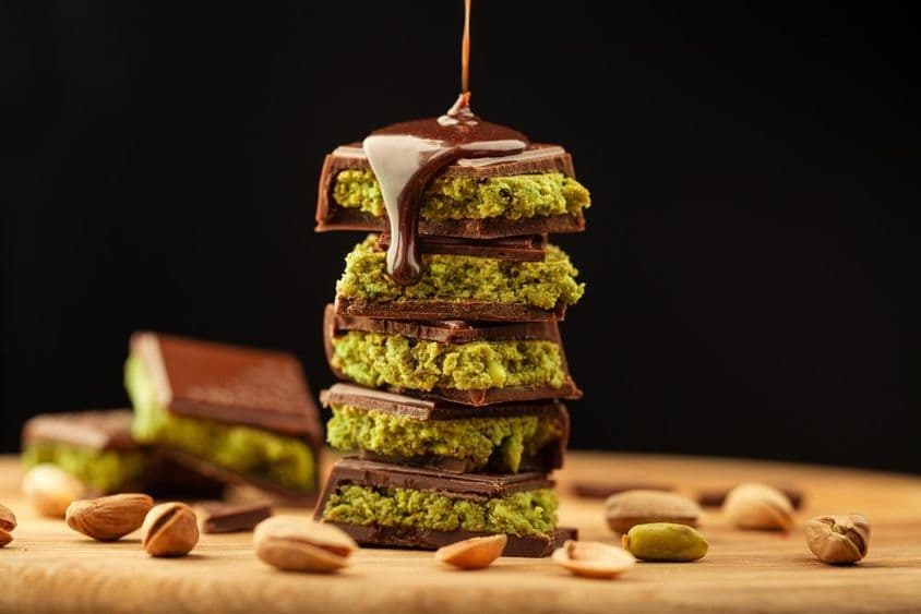 Chocolate de Dubái con pistachos y chocolate rociado sobre una mesa.