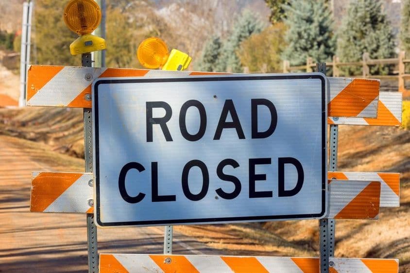 Señal de cierre de carretera con franjas naranjas.