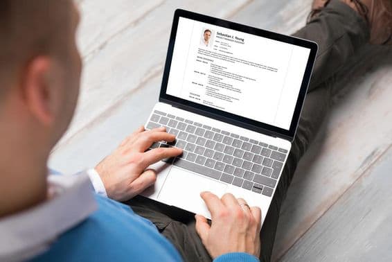 Una persona escribiendo su currículum en una laptop.
