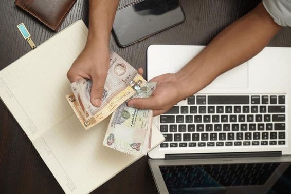 Un hombre contando un fajo de billetes de dirham de los Emiratos Árabes Unidos.