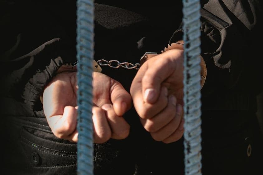 Un hombre esposado detrás de las rejas en la comisaría.