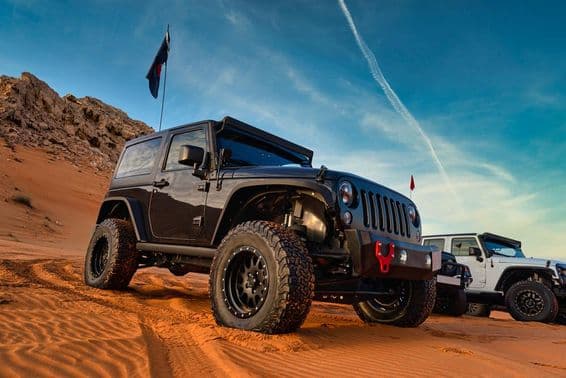 Jeep Wrangler en una aventura todoterreno sobre una duna de arena en el desierto rojo de Dubái.