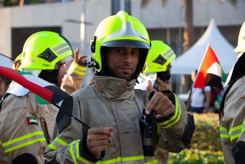 Bomberos de los EAU caminando con la bandera de los Emiratos en la ocasión de la fiesta nacional.