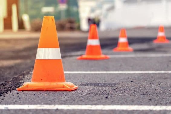 Filas de conos de tráfico naranja brillante en una carretera de asfalto.