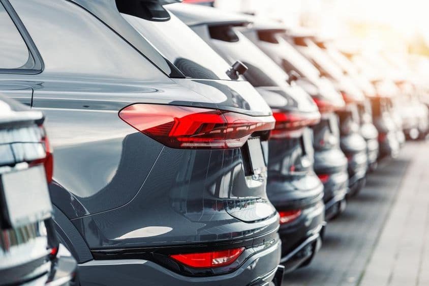 Vista trasera de una flota de carros SUV modernos nuevos en el estacionamiento de un concesionario.