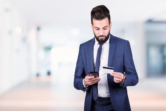Empresario árabe sosteniendo un smartphone y una tarjeta de crédito.