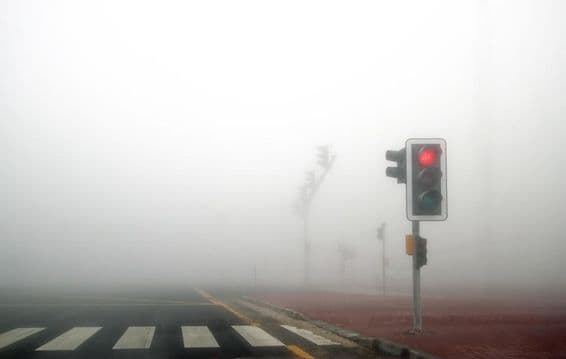 Niebla en una carretera de Dubai, semáforo rojo parpadeando.