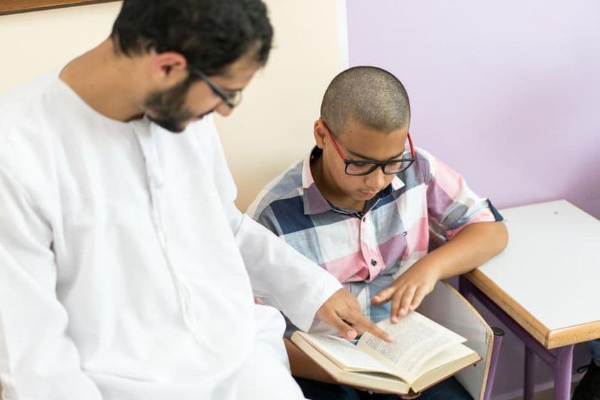 Joven maestra árabe estudiando con un escolar.