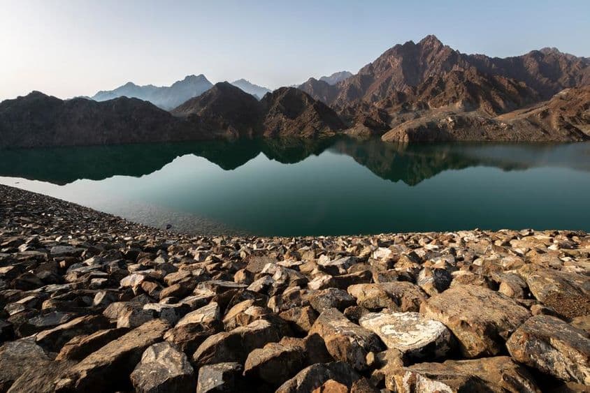 Presa de Hatta y montañas, vista impresionante reflejando rocas y montañas al amanecer.