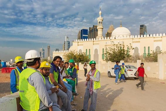 Trabajadores de construcción tomando un descanso junto a una mezquita en el moderno centro de Dubái.