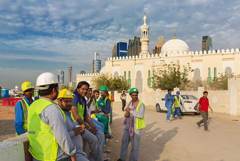 Trabajadores de construcción tomando un descanso junto a una mezquita en el moderno centro de Dubái.