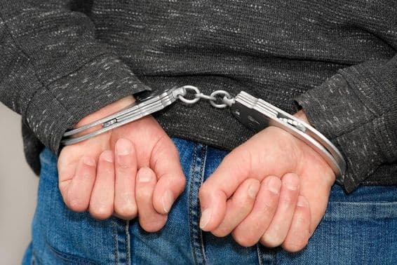 Un criminal esposado detenido por crímenes.