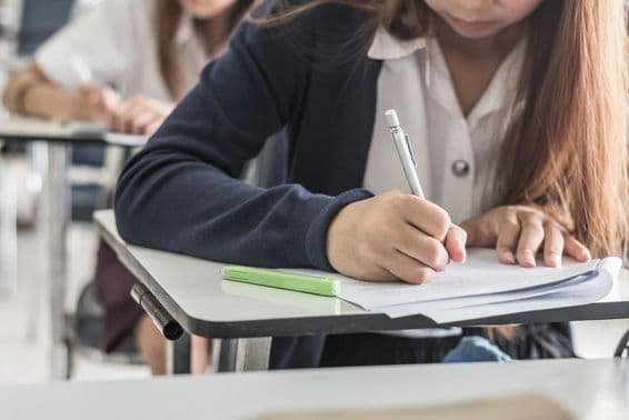 Estudiante de escuela escribiendo un examen en el aula.