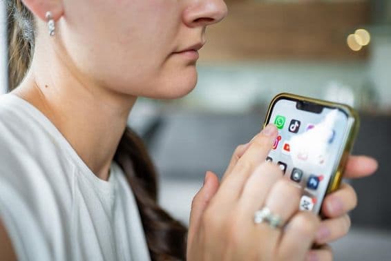 Mujer sosteniendo un iPhone con la aplicación de chat de WhatsApp en la pantalla.