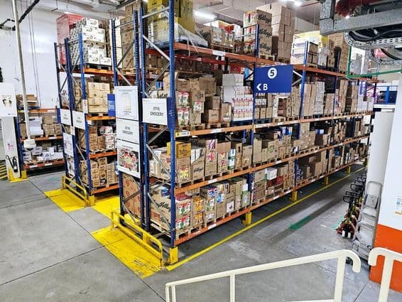 Almacén con sistemas de estanterías, categorías de productos etiquetadas y señales de seguridad que ayudan a operaciones fluidas.