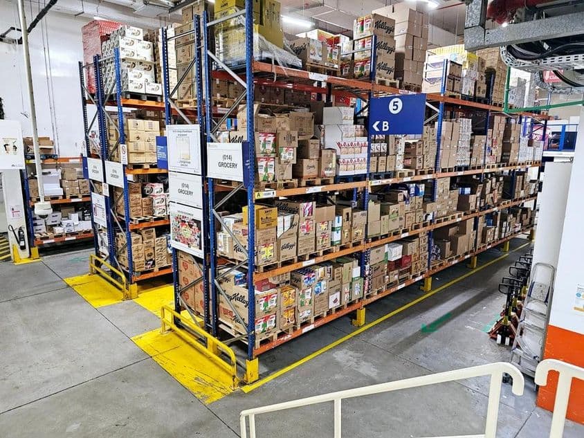 Almacén con sistemas de estanterías, categorías de productos etiquetadas y señales de seguridad que ayudan a operaciones fluidas.