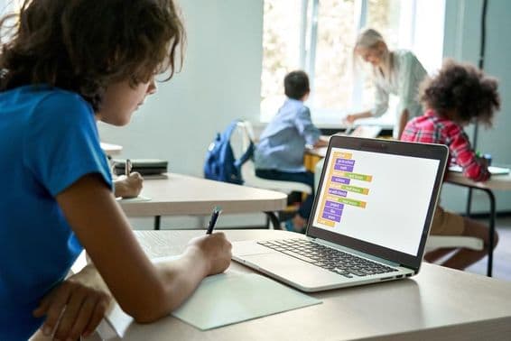 Estudiante de secundaria usando una laptop para introducir datos de programación.