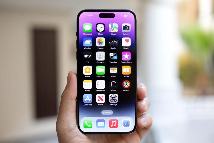 Hombre sosteniendo un iPhone 15 Pro Max con iOS 17 en la pantalla.