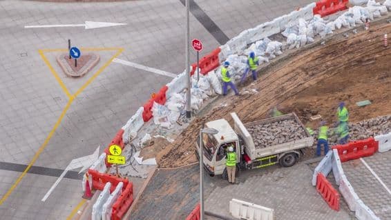 Proceso de reparación de aceras con muchos trabajadores de construcción y equipo rompiendo acera y concreto.
