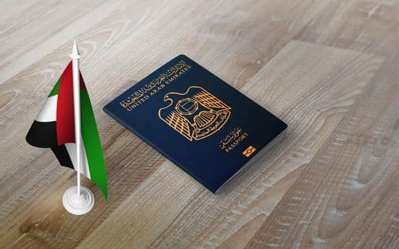 Pasaporte de los Emiratos Árabes Unidos sobre una superficie de madera, con una bandera nacional.
